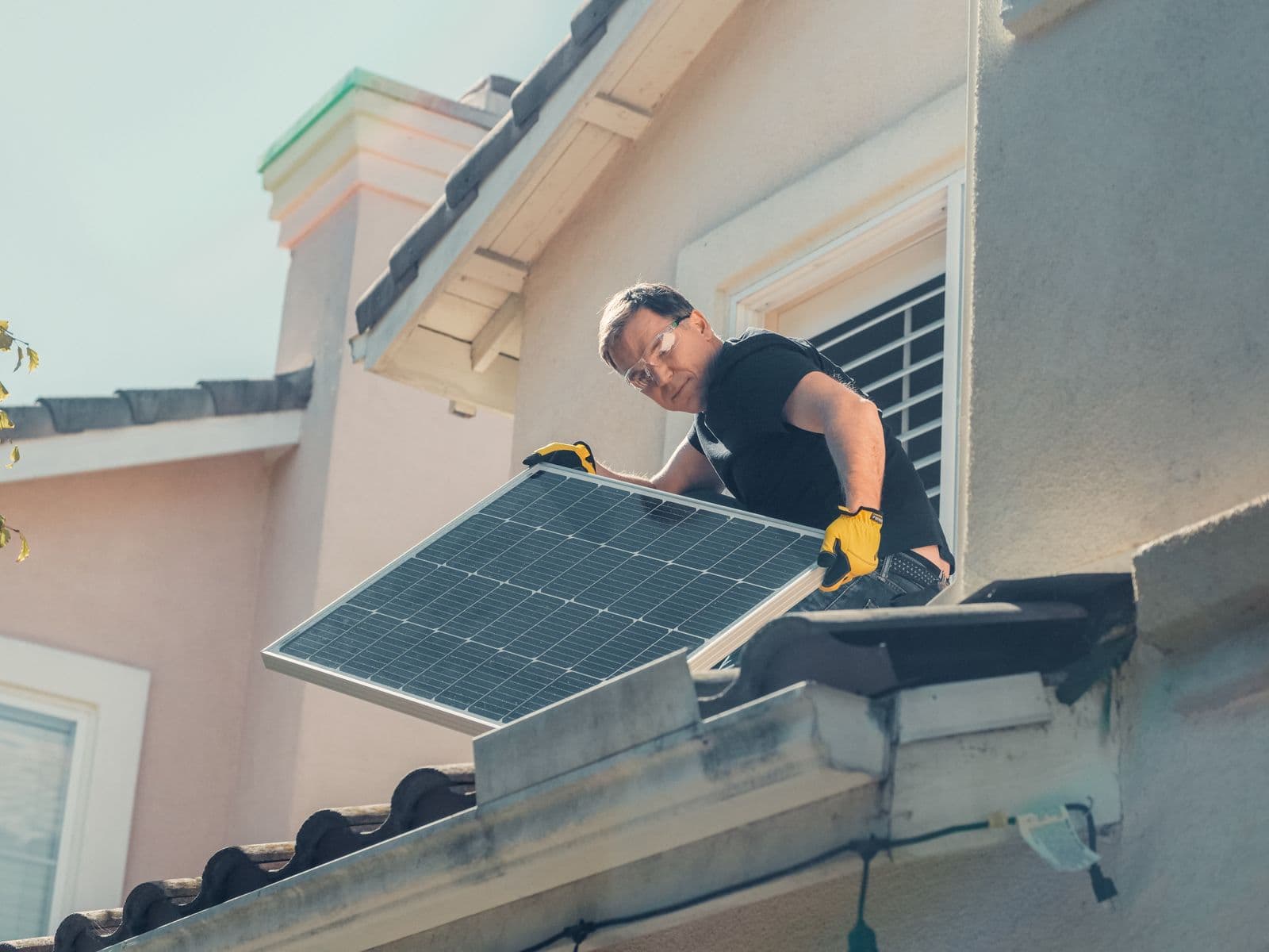 Technicien installant un panneau solaire sur le toit d'une maison individuelle